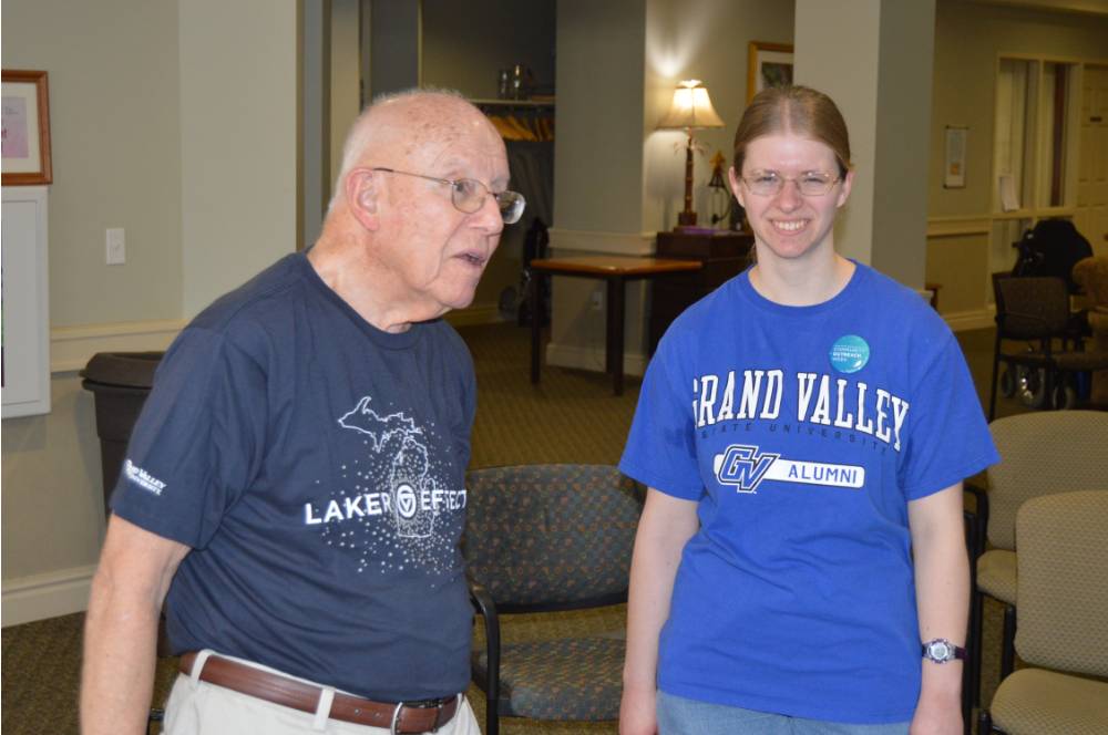 A volunteer and a senior play a game of Wii Bowling together.